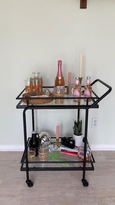 a shelf with bottles and candles on it in the middle of a room next to a wall