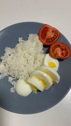an egg, rice and tomato are on a blue plate with a knife next to it