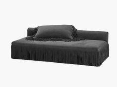 a black couch with fringe trim and pillows on it's back end, against a white background