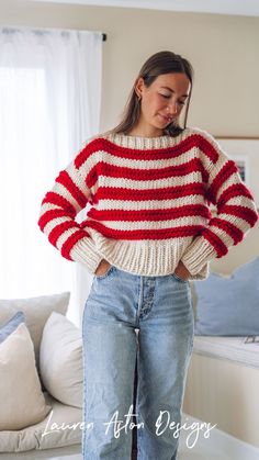a woman standing in front of a couch wearing a red, white and blue striped sweater