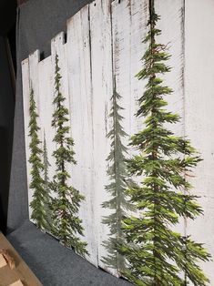 three pieces of wood with pine trees painted on the side and one piece has been cut out