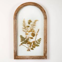 an old wooden frame with pressed flowers in it on the wall next to a white wall