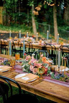 an outdoor dinner table set with candles and flowers