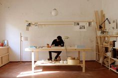 a person sitting at a table working on some type of project in an unfinished room