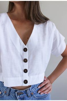 a woman with her hands on her hips wearing a white shirt and blue jean shorts