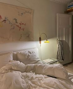 an unmade bed in a bedroom with a painting hanging on the wall above it