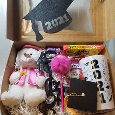 a box filled with lots of items including a teddy bear and graduation cap on top