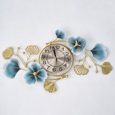 a clock with blue flowers and leaves on the face is shown in gold, against a white background