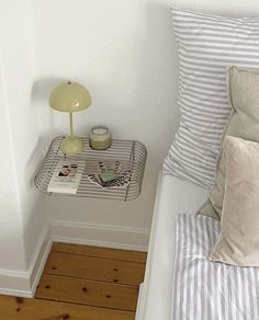 a white bed sitting next to a small table with a lamp on top of it