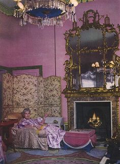 an old photo of a woman sitting in a room with pink walls and gold furniture
