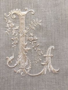 an embroidered monogram is shown on the side of a piece of linen with flowers and vines