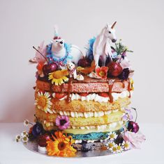 a multi layer cake decorated with figurines, flowers and other things on top