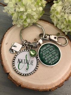 a keychain with a green and white tag on it sitting next to some flowers