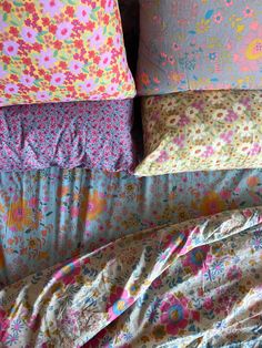 four pillows stacked on top of each other in front of a bed with floral sheets