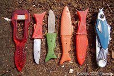 five different colored fish shaped knives lined up in a row on the ground next to each other