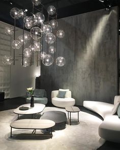 a living room filled with white furniture and lots of glass balls hanging from the ceiling