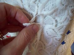 someone is stitching the lace on a white piece of cloth with scissors and thread