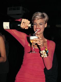 a woman in a red dress drinking from a wine glass with a straw in her mouth