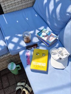 there is a yellow book and some sunglasses on the blue couch next to each other