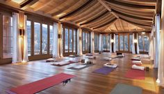 a large room with many yoga mats on the floor, windows and wooden ceilinging