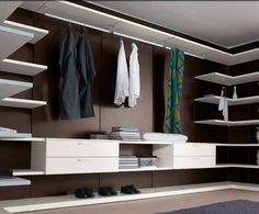 a modern walk in closet with shelves and hanging clothes on the wall, carpeted floor