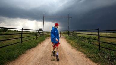 A man looks back over his shoulder at dark storm clouds