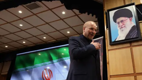 EPA Parliamentary Speaker Mohammad Baqer Qalibaf walks past a photo of Supreme Leader Ayatollah Ali Khamenei after speaking at a press conference in Tehran (3 June 2024)