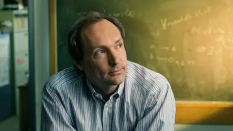 Getty Images Sir Tim, looking younger in front of a chalkboard with mathematical equations written on it