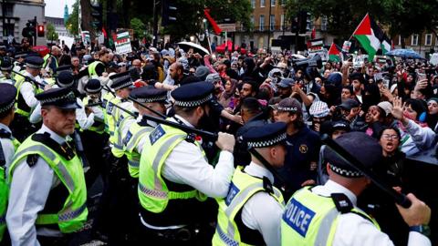 Police officers stand in front of a crowd of protesters during a pro-Palestinian rally in London on 28 May