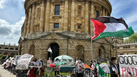 Protesters with banners and a Palestinian flag flying outside the Radcliffe Camera