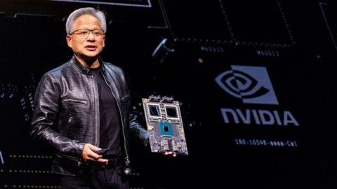 Nvidia's chief executive Jensen Huang holds a mock computer chip delivers his keystone speech ahead of Computex 2024 in Taipei on June 2, 2024.