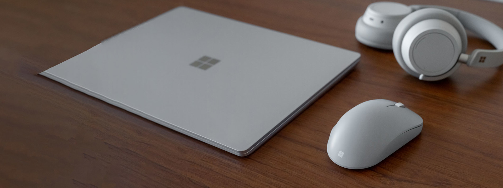 A Surface laptop, mouse, and headphones on a desk.