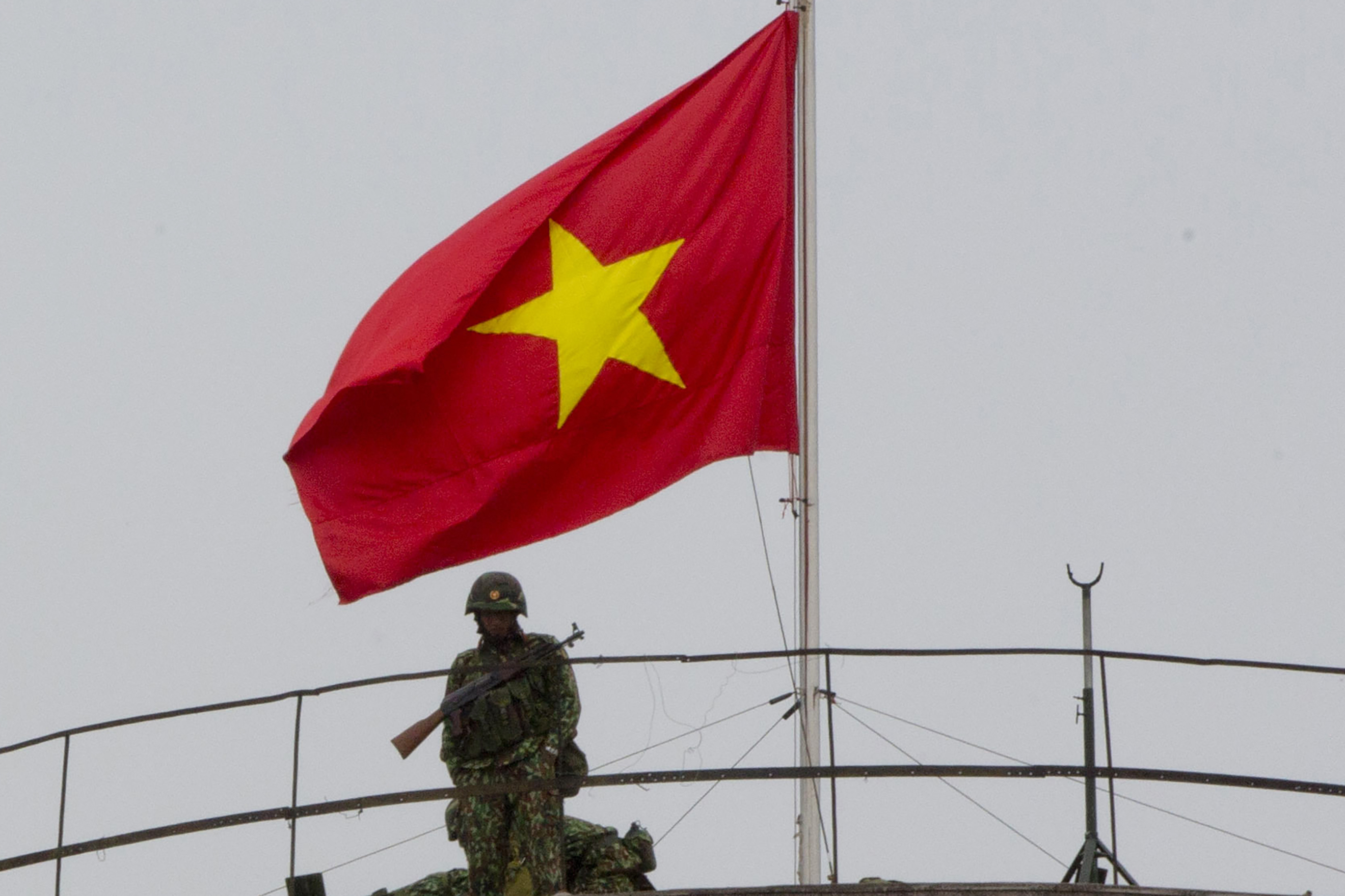 FILE - A flag of Vietnam is seen as a soldier watches from a top of a building neighboring Government Guesthouse and a hotel in Hanoi, Vietnam, on Feb. 24, 2019. Human rights groups urged Thailand on Thursday, June 13, 2024, not to extradite a Vietnamese activist detained in Bangkok, saying that he could be at risk if handed back to Vietnam. (AP Photo/Gemunu Amarasinghe, File)