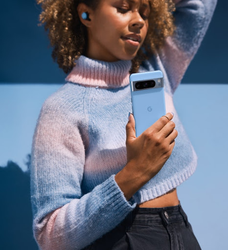 A person holds their Pixel phone in Bay color. They stand against a bay-colored background.