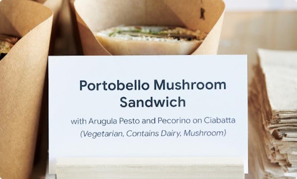 Photo of signage for a portobello mushroom sandwich. The ingredients read: with arugula pesto and pecorino on ciabatta (vegetarian, contains dairy, mushroom).