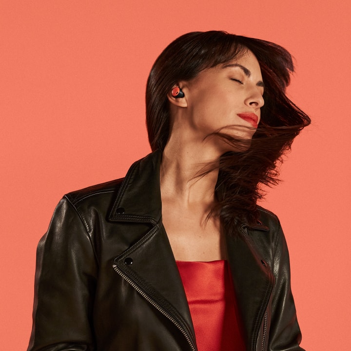 A person in a leather jacket dances to music playing in their Coral Pixel Buds Pro