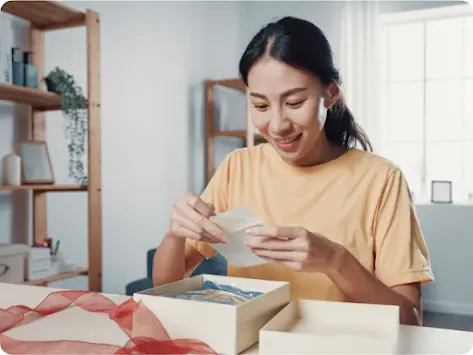 Frau, die ein Geschenk öffnet und die beiliegende Karte liest