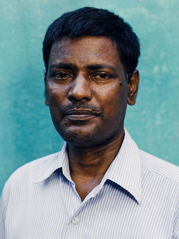 Elumalai, a diabetic patient, looks at the camera with a serious demeanor. He's wearing a shirt and stands in front of a blue wall.