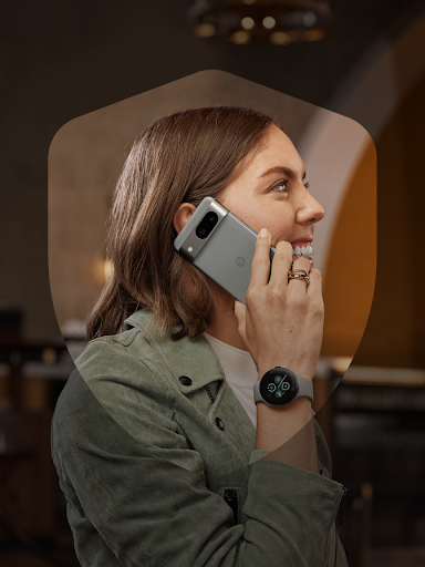 Een glimlachende Android-gebruiker neemt beveiligd een telefoongesprek aan terwijl die hun Pixel Watch 2 toont. De gebruiker is omlijst door een schildicoon.