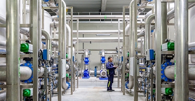Un technicien vérifiant des tuyaux qui vont du sol au plafond dans une usine de traitement des eaux au sein du centre de données Google situé en Belgique.