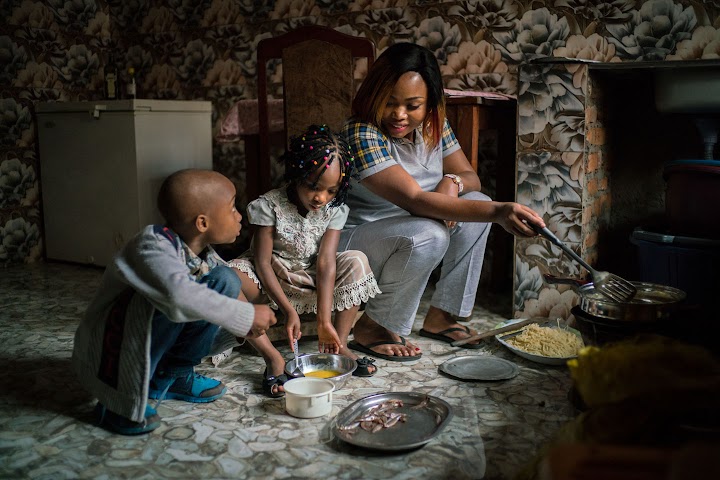 Riziki making breakfast with two of her children.