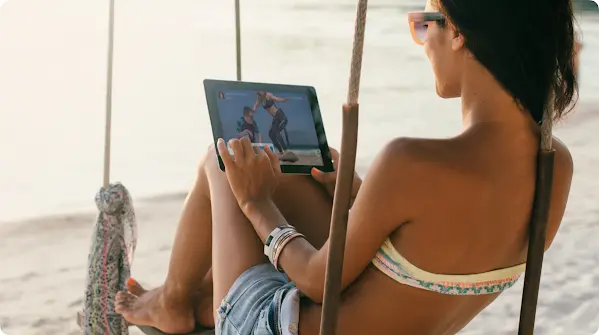 一名女士在海灘上看著平板電腦螢幕
