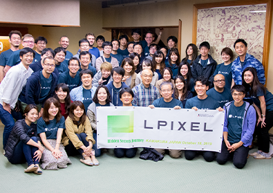 The team of LPixel surrounds a banner revealing their company’s name.
