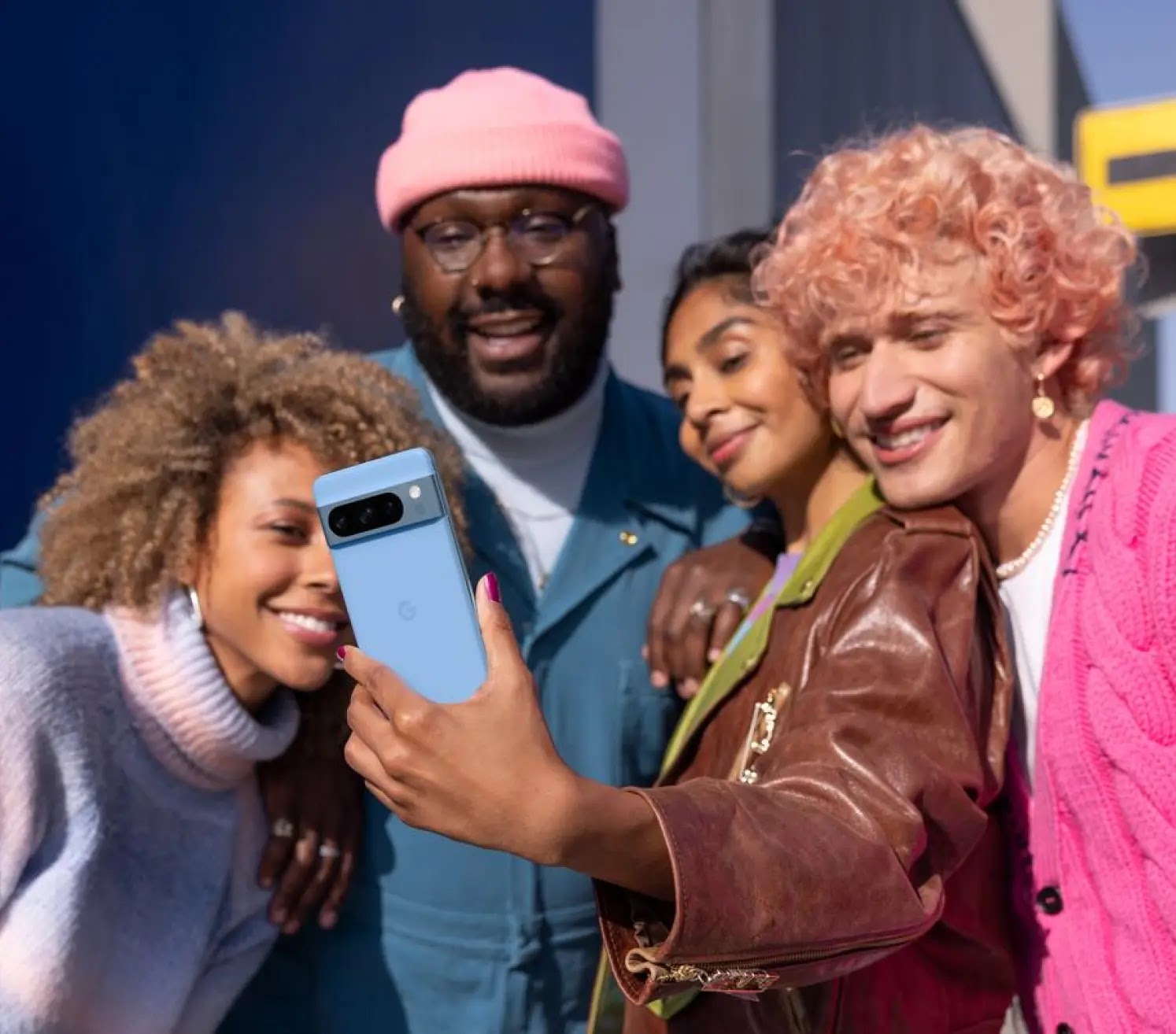 Un groupe de personnes prend un selfie avec un téléphone Pixel 8 Pro bleu.