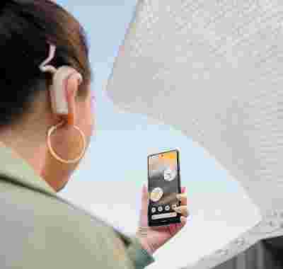 Eine Person mit einem Cochlea-Implantat schaut auf ein Android-Smartphone.