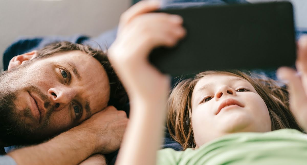 الأب والابن يشاهدان فيديو على الهاتف معًا.