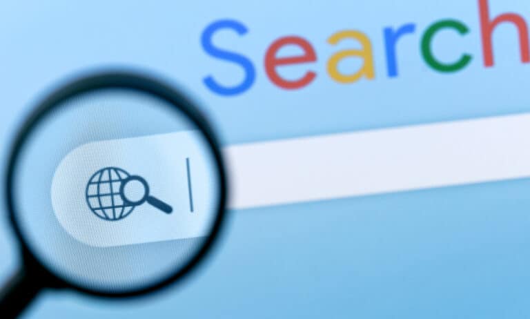 A magnifying glass hovers over the Google search bar, symbolizing the need for scrutiny and precision in AI-powered search results to avoid misinformation and "hallucinations."