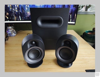 Square black speaker behind 2 cylindrical shaped speakers