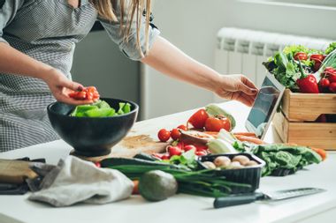 Woman utilizing tablet in the kitchen while cooking