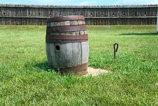 An rusty antique barrel sits on a lawn.
